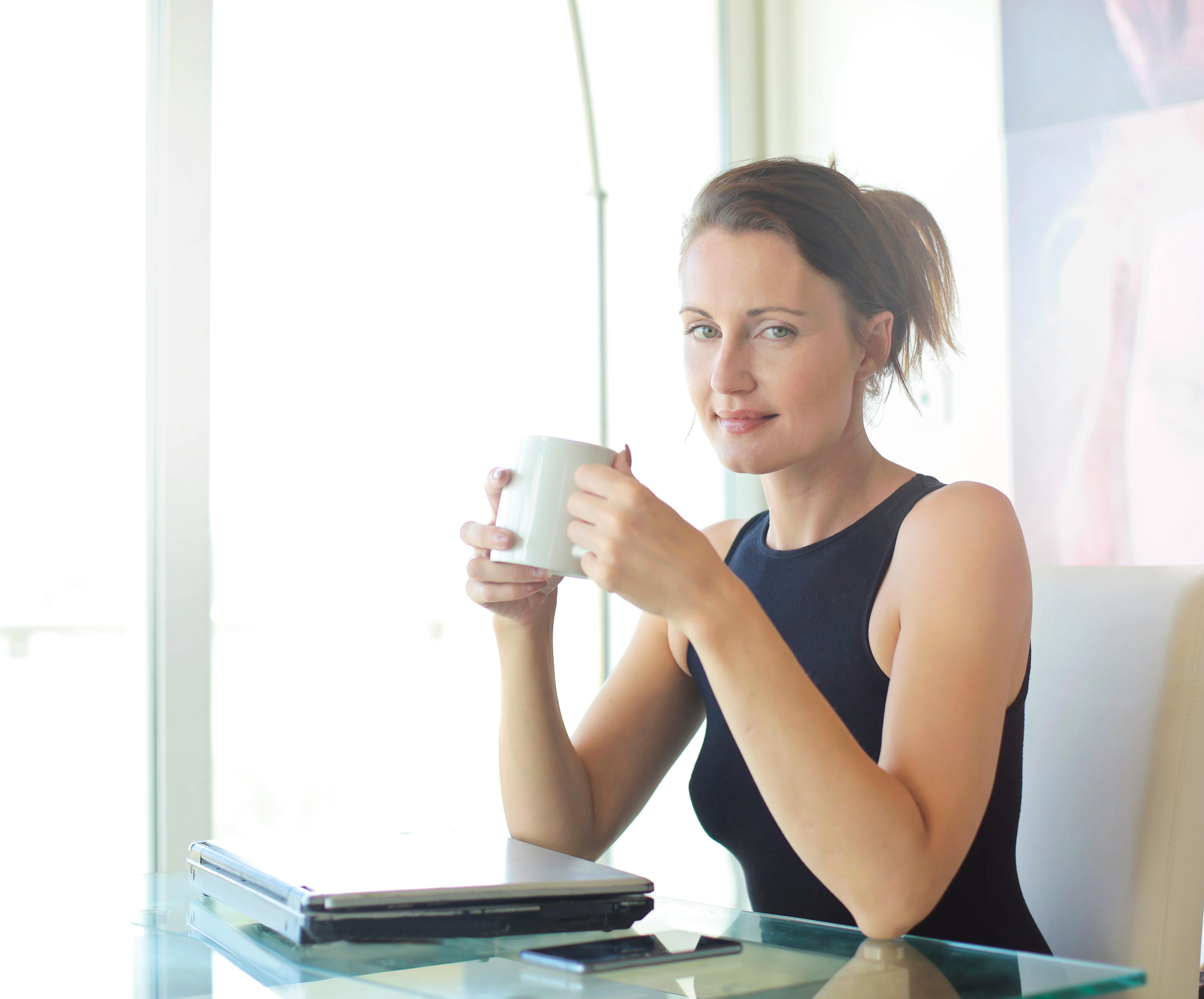 Professional copywriter sitting behind a laptop with a coffee while working on a client project