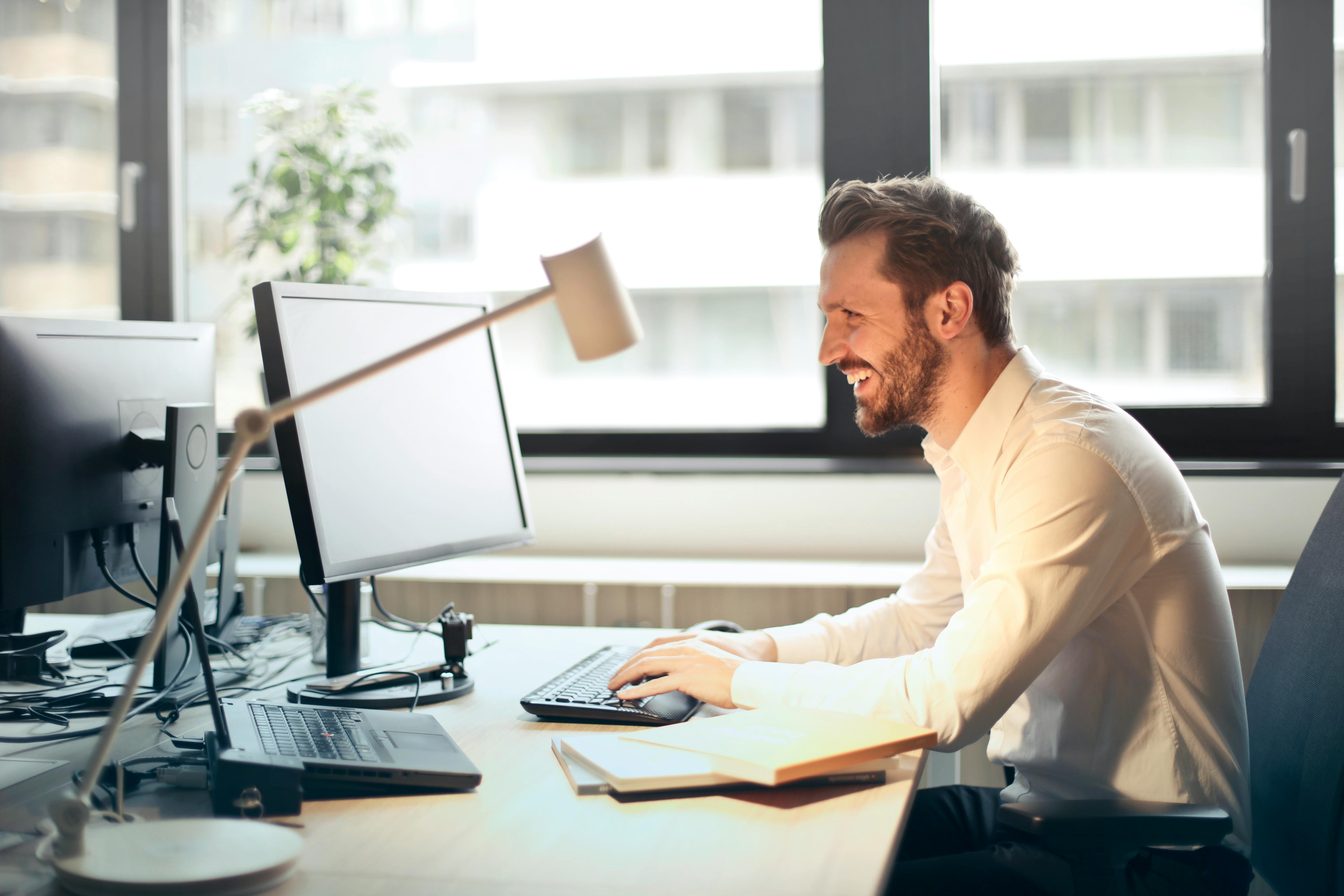 Copywriter at a desk, smiling at what they're viewing on the monitor